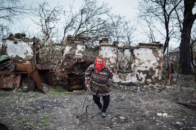Женщина у разрушенного дома в поселке Саханка Донецкой области. Саханка — село на юге ДНР, которое находится на линии соприкосновения. До конфликта в Донбассе здесь проживало более тысячи человек, а сейчас численность населения сократилась в разы.