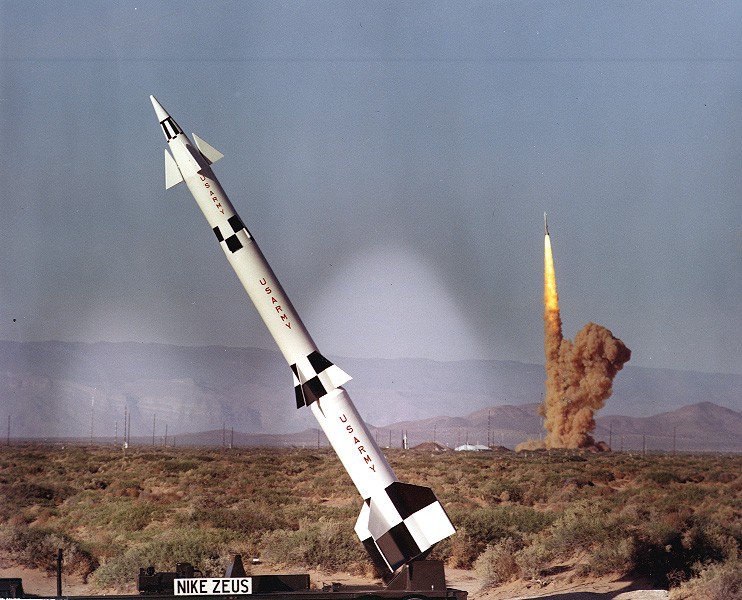 Ракета Nike Zeus B на переднем плане - статическая экспозиция в Уайт-Сэндс, а на заднем плане - испытательный пуск другой Zeus B.