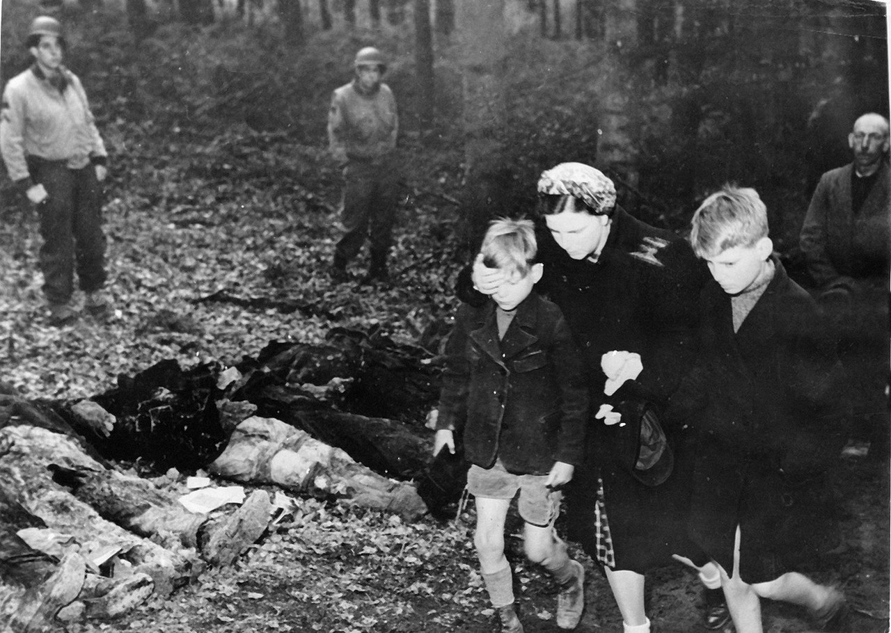 Немцы проходят мимо тел 57 советских граждан, которые были убиты эсэсовцами и похоронены в братской могиле незадолго до прихода американских войск.