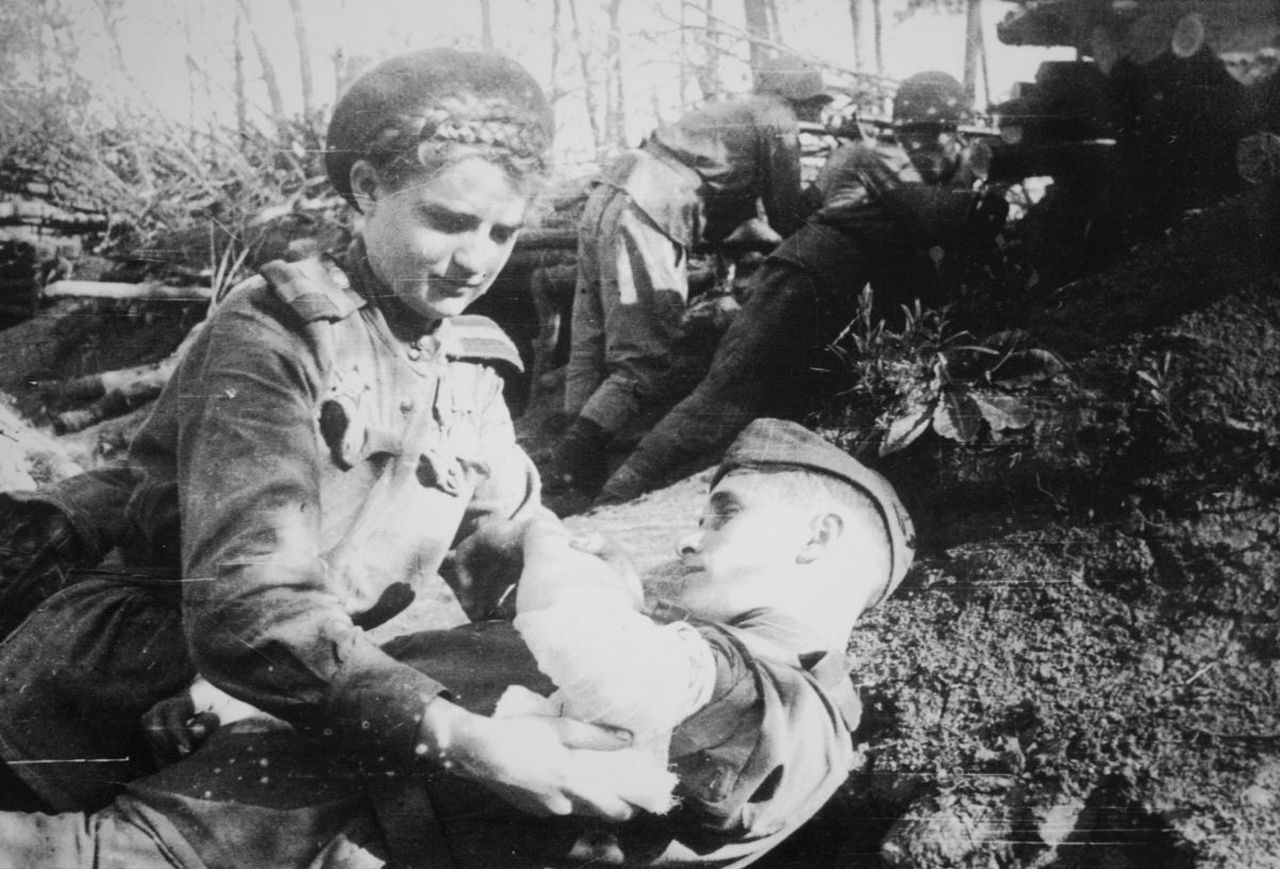 Санинструктор старшина медицинской службы Т.А. Капинос перевязывает раненого бойца. 1944 г.