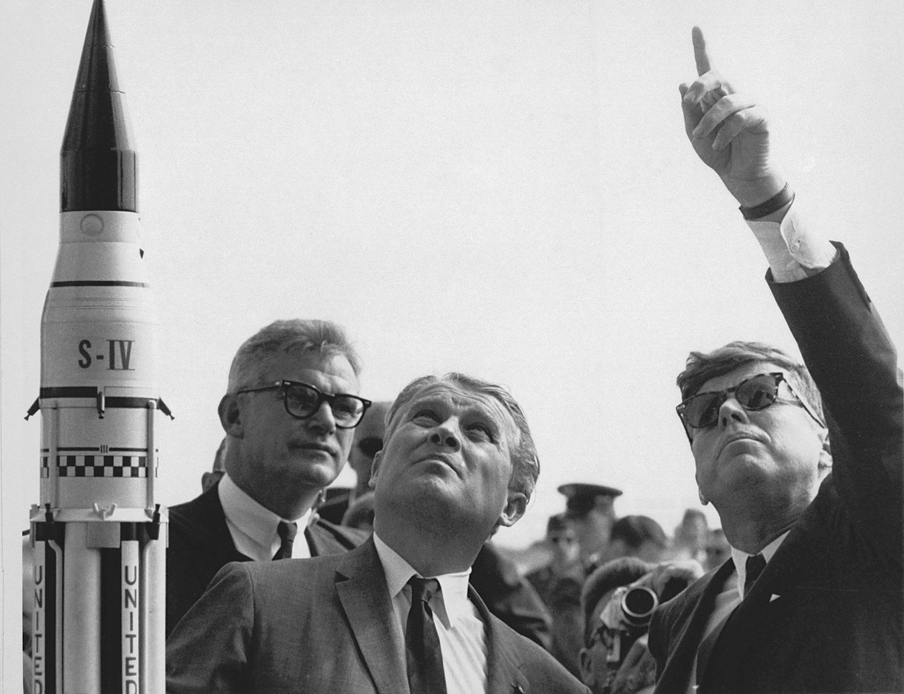Директор Центра космических полётов им. Маршалла (MSFC) доктор Вернер фон Браун (в центре) объясняет систему запуска «Сатурн» президенту США Джону Ф. Кеннеди (справа) на мысе Канаверал, Флорида.