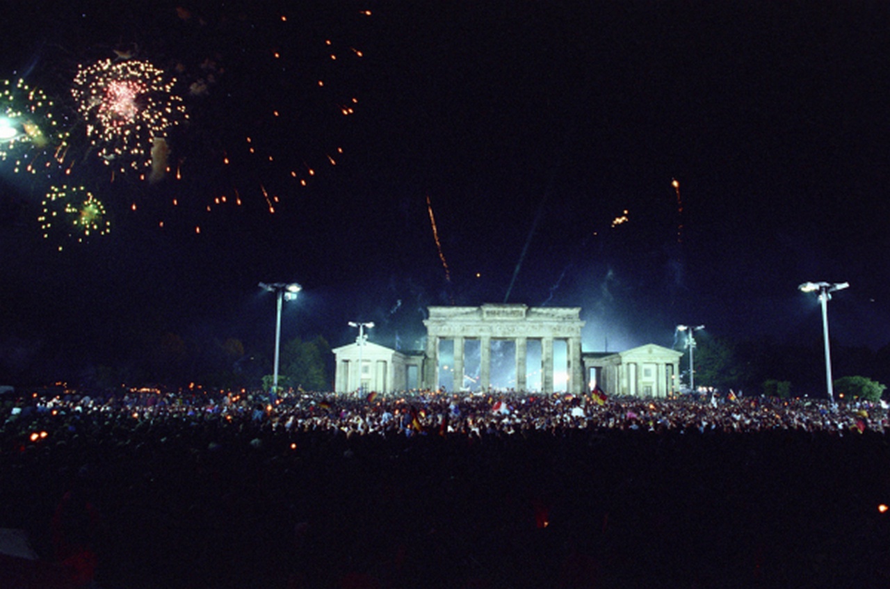 Жители Берлина празднуют объединение ГДР и ФРГ на площади у Бранденбургских ворот, октябрь 1990 г.