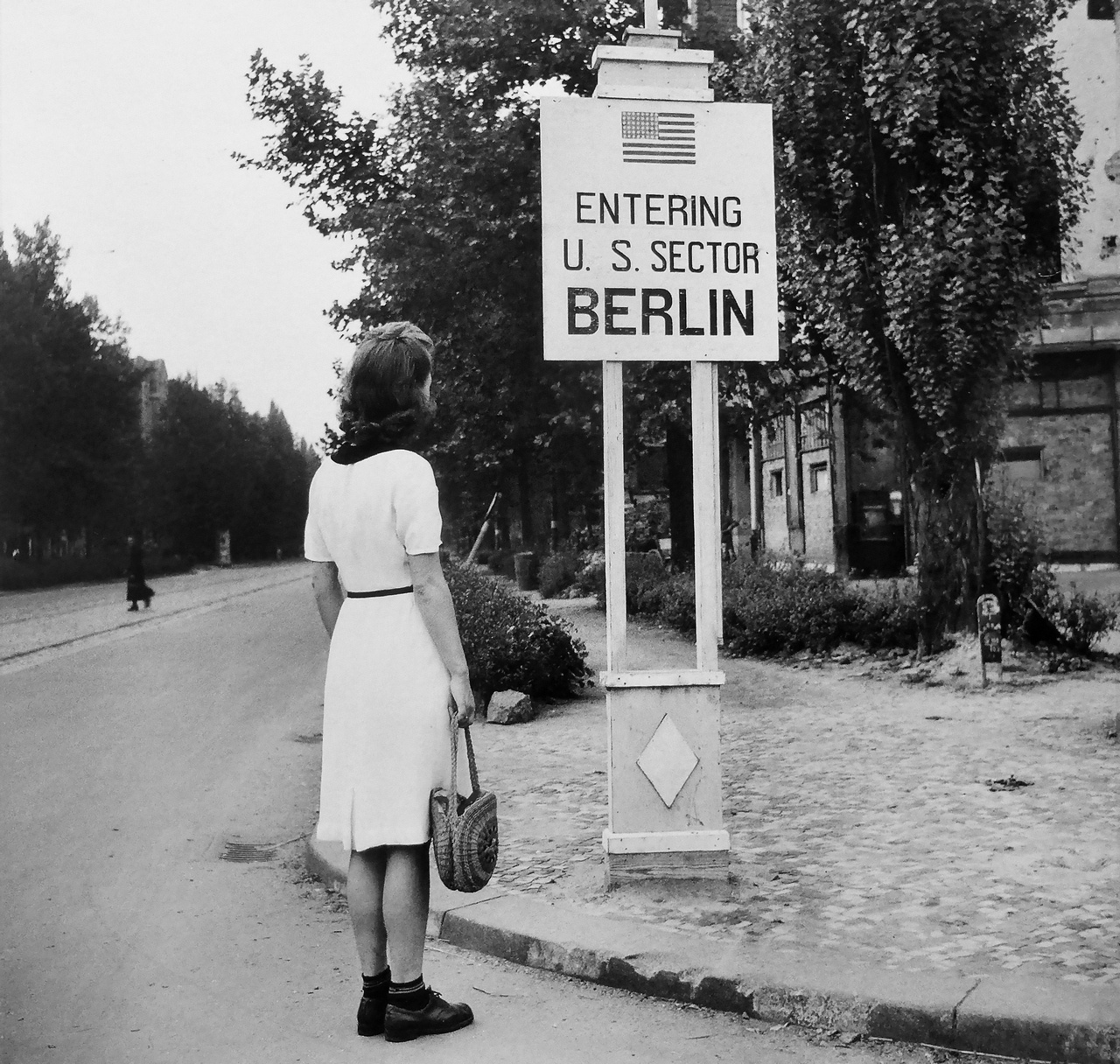 Девушка смотрит на указатель на границе американского сектора в Берлине, август 1945 г.