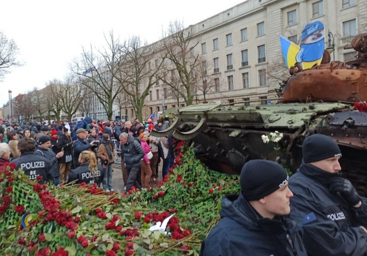 Люди у подбитого в зоне СВО танка Т-72 выступили с мирными лозунгами и возложили к боевой машине цветы в знак протеста против поставок оружия Киеву.