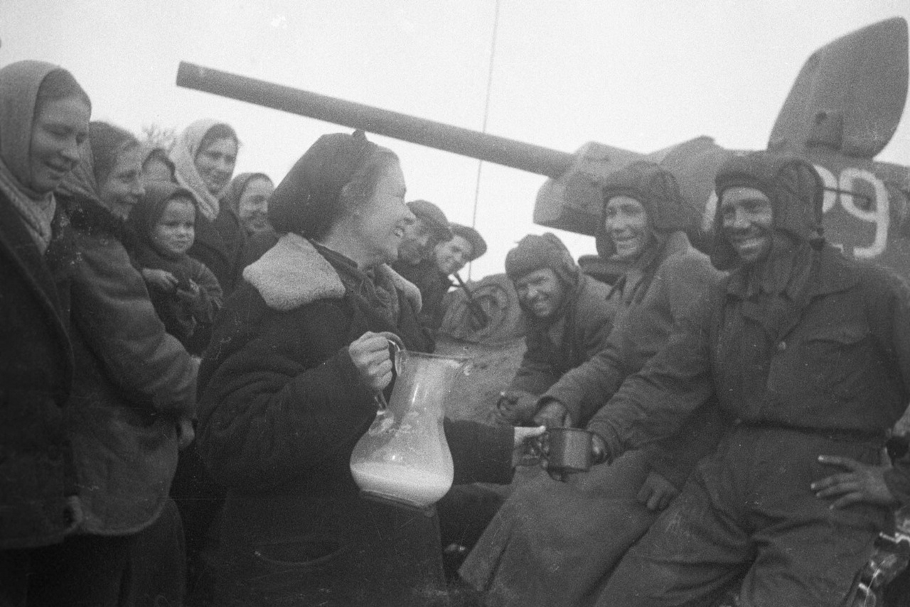 Жительница освобождённого польского села угощает экипаж советского танка молоком, 1944 г.