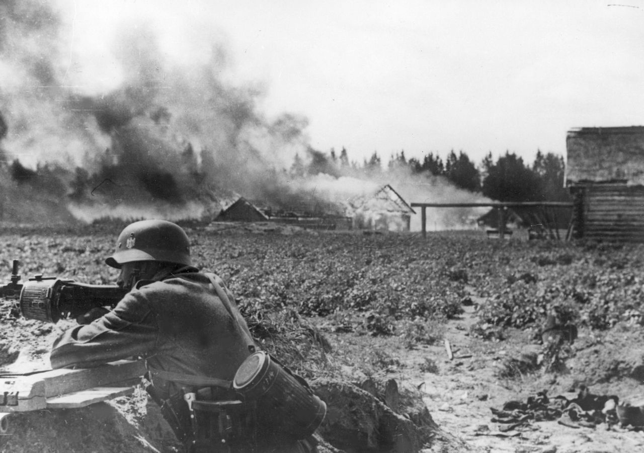 Немецкий пулемётчик на околице горящей советской деревни во время антипартизанской операции.
