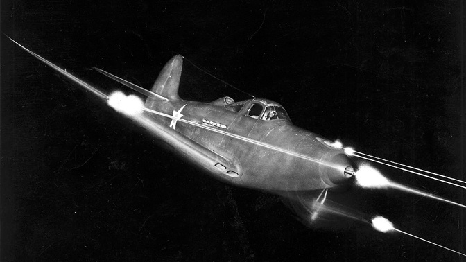 Bell P-39 Airacobra в полете стреляет из оружия ночью.<figcaption class=
